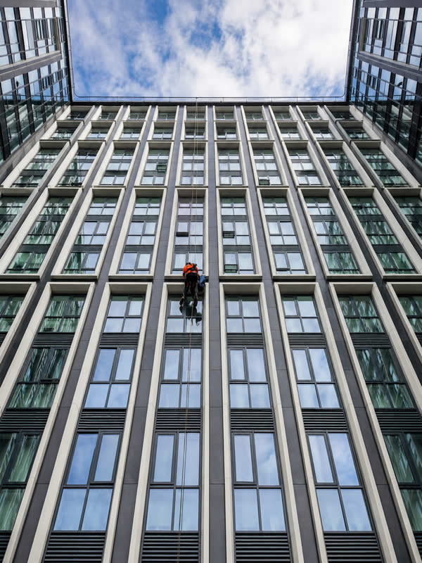 Close-up portrait crop of a technician against a high-rise glass facade