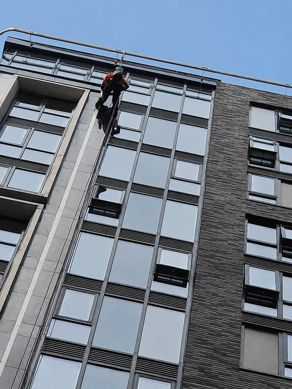 Diagonal close-up angle of a technician working on a high-rise facade