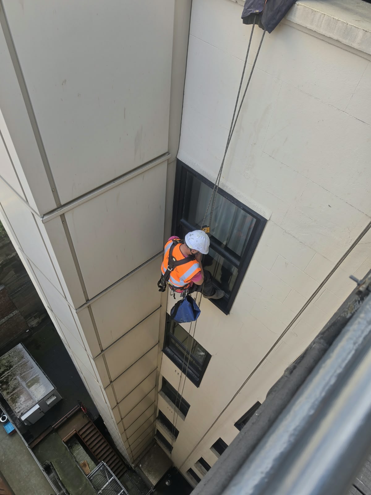 Rope access technician working on an external window frame