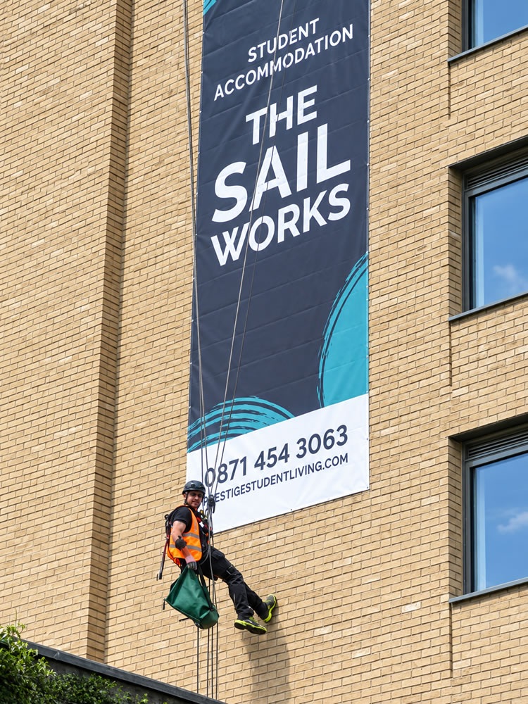 Rope access technician beside the installed printed signage on the brick elevation