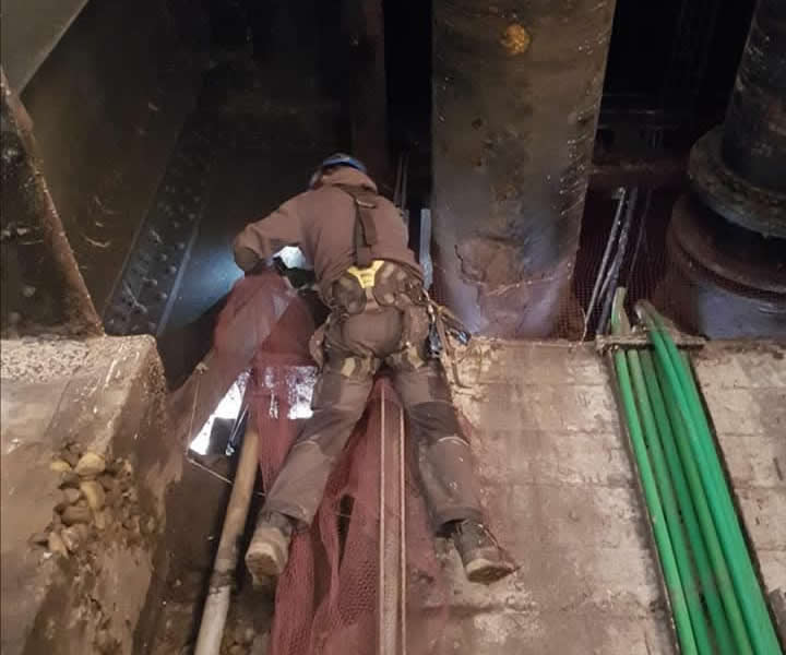 Rope access technician working beside pipework inside the North Tower