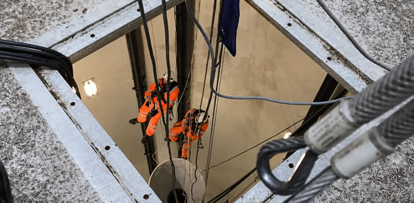 Exterior view looking into a ballast tank opening with technicians working inside