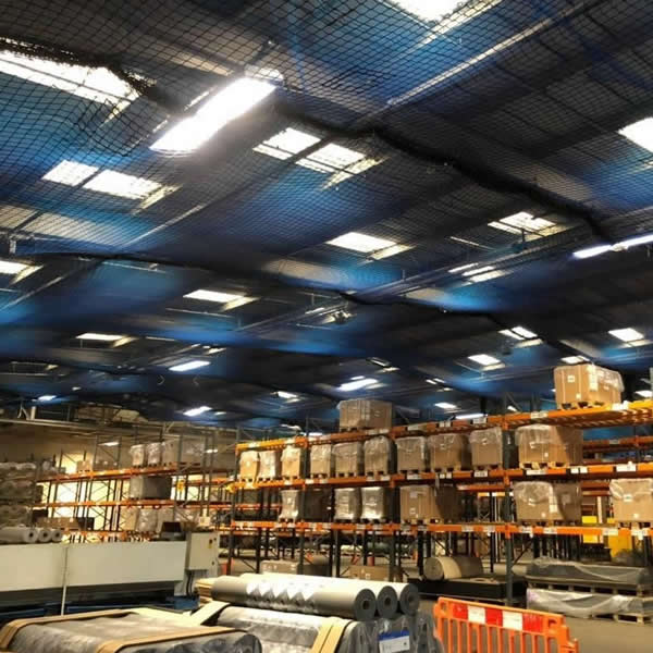 Bird netting installed high in the roof of a large industrial warehouse