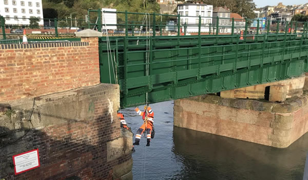 Two rope access technicians repointing the underside of a bridge