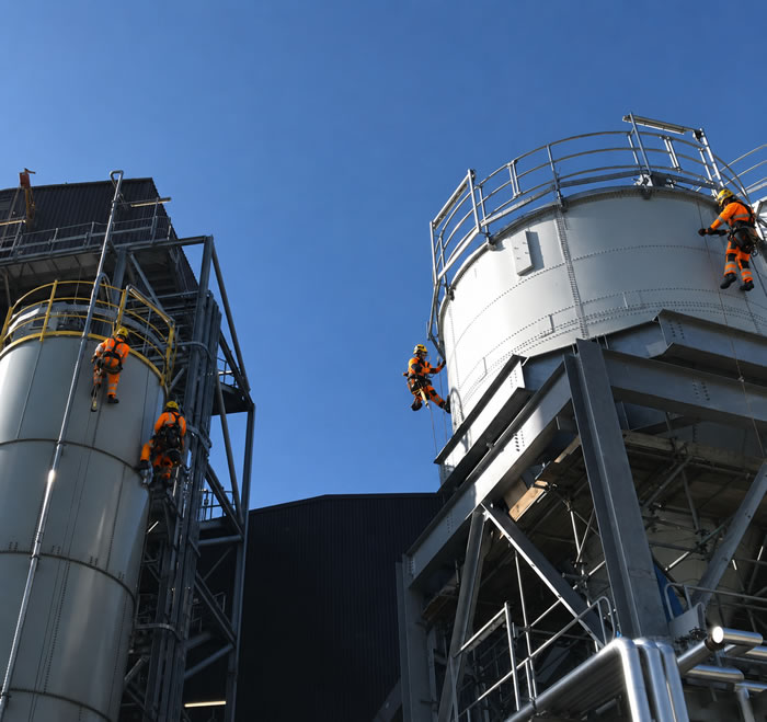 Large industrial silo being repainted via rope access